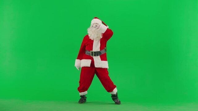 Portrait of man dressed as Santa on chroma key green screen background. Santa Claus in red outfit dancing funny old dance with hand gestures.