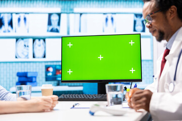African american medic points at green screen on computer while he consults his patient, exploring treatment plans on health insurance. Physician gives medical advice to ill woman.