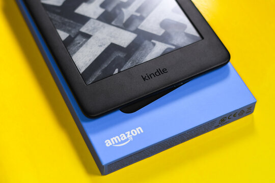 Unboxing Amazon Kindle in a yellow background. A digital book in a box. Black e-book reader.