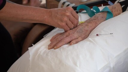 A nurse setting up an IV on an elderly patient