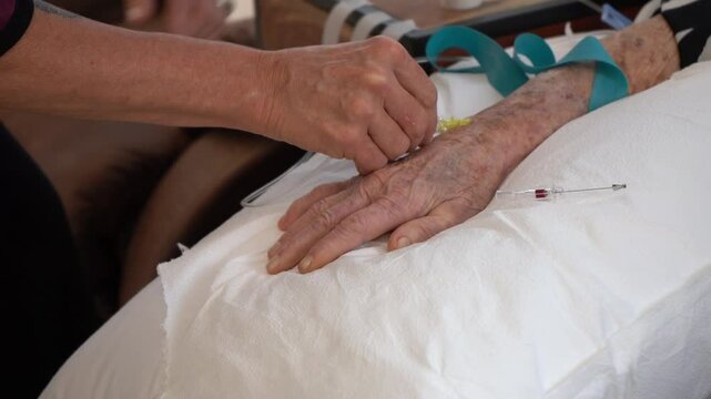 A nurse setting up an IV on an elderly patient