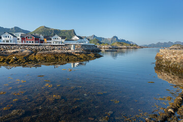 Fototapeta premium Houses on the rocky shore with mountains in background in Kabelvag city, Lofoten Norway