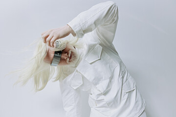 Model in a white outfit posing against a minimalistic gray background, showcasing avant garde...