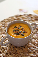 Pumpkin and potato creamy soup, bowl of grapes, jars of nuts and autumn leaves on the table. Selective focus.