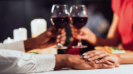 Unrecognizable Black Couple Holding Hands And Clinking Glasses On Romantic Date In Restaurant. Cropped, Selective Focus