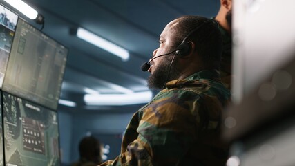 Military dispatcher using headphones microphone, offering information to commanders fighting on...
