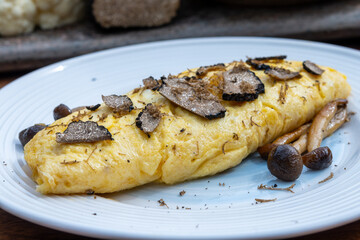 French omelette with mushrooms, fresh farmers eggs and black summer truffle mushroom in pieces for...