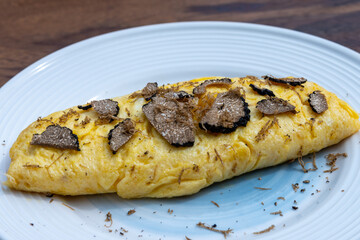 French omelette with mushrooms, fresh farmers eggs and black summer truffle mushroom in pieces for making truffle dishes with tasty aroma