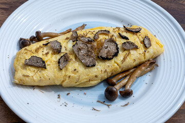 French omelette with mushrooms, fresh farmers eggs and black summer truffle mushroom in pieces for making truffle dishes with tasty aroma