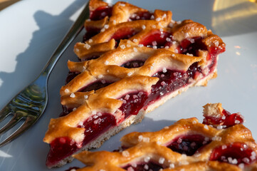 Homemade open sour cherry pie, delicious sweet dessert served in pieces outdoor in garden