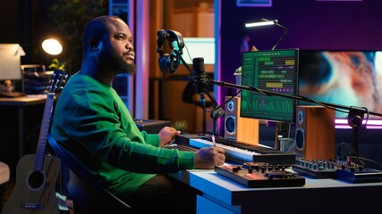 Composer writes verses and ideas to develop original song in home studio before recording new audio files. Songwriter using musical equipment and his imagination, artist composes music. Camera A.
