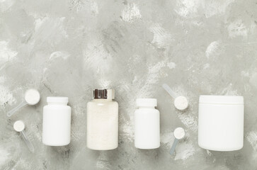Jars with protein powder on concrete background, top view. Sports nutrition concept