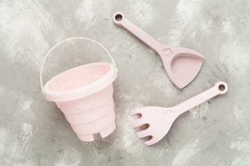 Cute toys for playing with sand on concrete background, top view