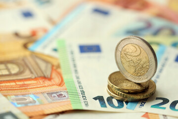 Two euro coin lies on huge amount of different euro dollars banknotes