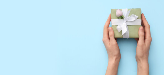 Female hands with gift box and beautiful rose on blue background. International Women's Day