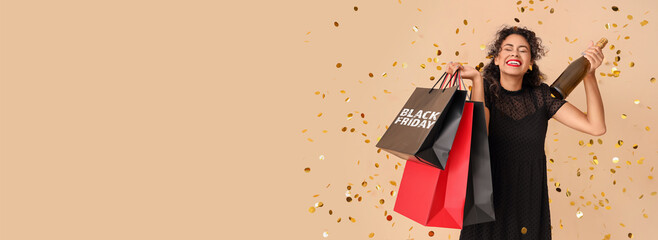 Beautiful African-American woman with shopping bags and bottle of champagne on beige background. Black Friday sale