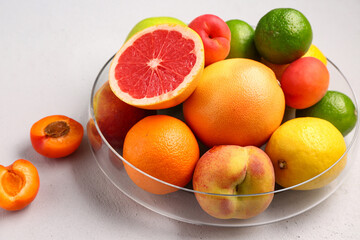 Bowl with different fresh fruits on grey background