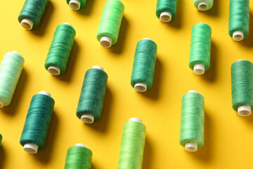 Composition with colorful thread spools on yellow background