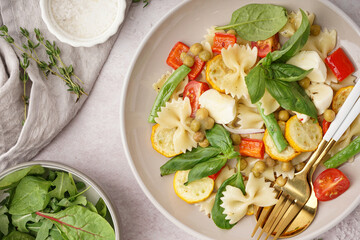 Plate of tasty pasta salad with peas and basil on white background