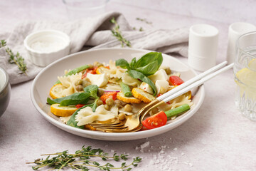 Plate of tasty pasta salad with peas and basil on white background