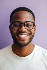 Obraz premium Young African American man with glasses, smiling brightly with confidence and joy, standing against a light lavender background.