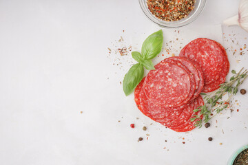 Slices of tasty salami on light background