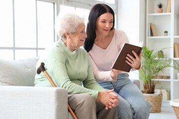 Senior woman and her daughter with book at home