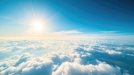 Fototapeta premium Beautiful aerial view from an airplane flying high above the clouds, with the bright sun shining and a vast blue sky extending endlessly