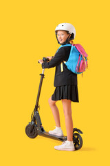 Cute schoolgirl in helmet with electric scooter on yellow background