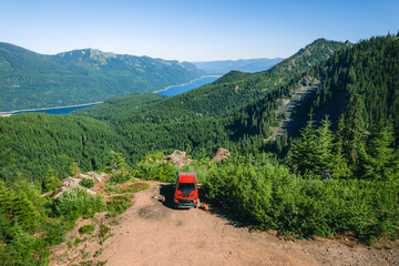 Aerial shot of shot of a pickup truck standing on the cliff with a backdrop of North Cascades Mountains and Lake Kachess in Snoqualmie Pass, Washington State.	
