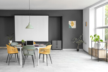 Fototapeta premium Modern office meeting room with projector screen round table colorful chairs and contemporary decor for business presentations