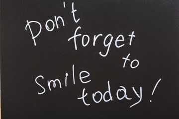 don't forget to smile today inscription, text with white chalk marker on black board, motivation...