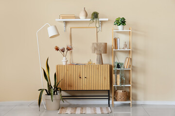 Interior of room with wooden commode, shelf unit and plants