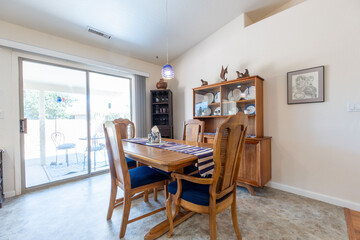 Bright dining area featuring a wooden table and chairs, with natural light streaming in from a sliding door
