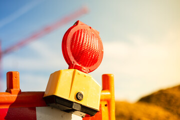 Yellow warning light on a construction site. Crane in background. Day, outside, sun.
