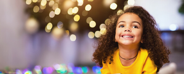 Enjoying Christmas holidays. Cheerful afro girl portrait near Xmas tree