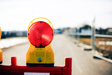 Warning light on empty road under clear sky.