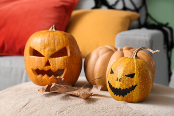 Halloween pumpkins with autumn leaf on pouf in living room, closeup