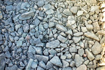 Gravel stones form a beautiful and rugged pattern in the morning sun. Day, outdoor. 
