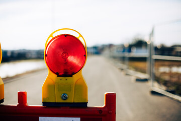 Flashing red construction lamp on road at daylight.
