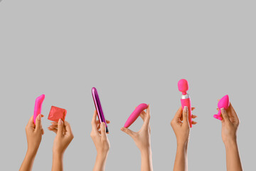 Women with sex toys and condom on grey background