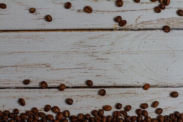 Granos de cafe Moka tostado sobre un fondo de madera blanca con relieve