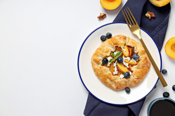 Fruit galette on plate, towel, fruits and jam on white background, space for text