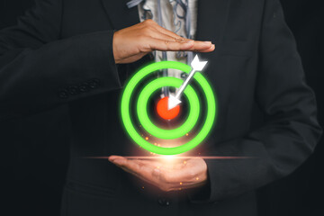 A businessman in a suit holding a glowing target with an arrow, symbolizing startup business goals,...