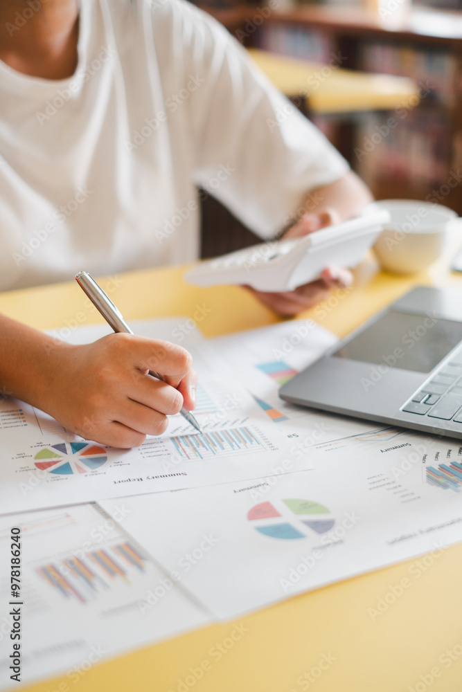 Poster close-up of a business professional analyzing financial data with charts and graphs on a desk, using