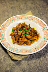 Showing a savory soy sauce chicken dish. This dish is served on a round ceramic plate decorated with floral motifs. Garnished with fresh green herbs and small slices of red chili