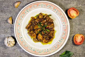 Showing a savory soy sauce chicken dish. This dish is served on a round ceramic plate decorated with floral motifs. Garnished with fresh green herbs and small slices of red chili