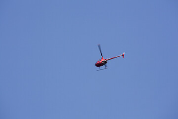 Small red touristic helicopter captured in the air above Downtown Portland, Oregon