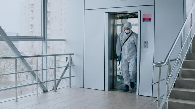 A healthcare worker wearing protective gear steps out of an elevator in a medical facility, showcasing the precautions taken during patient care in a clinical environment.