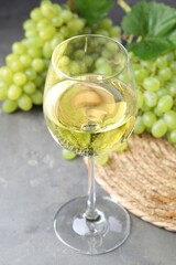 Fresh ripe grapes and glass of wine on grey table
